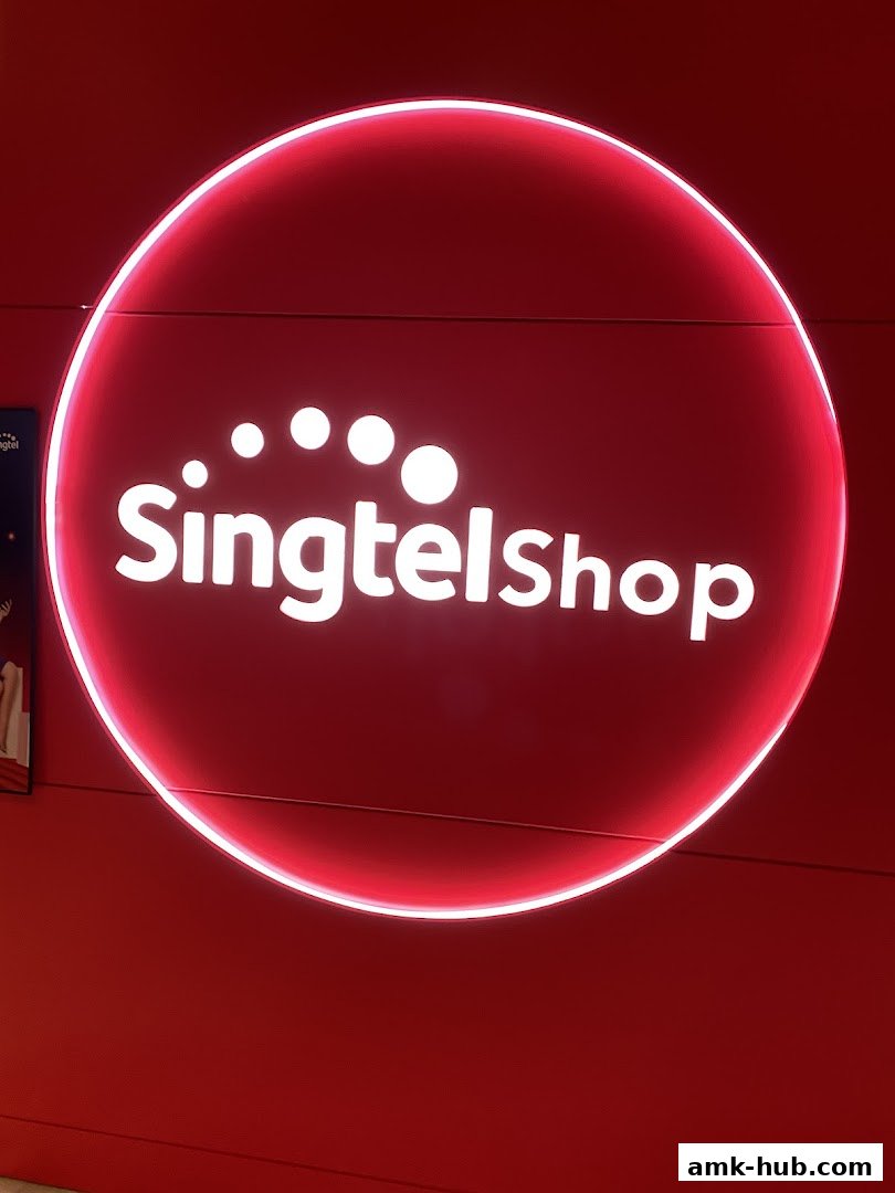 A bright red circular sign with the white text 'Singtelshop' and illuminated dots.