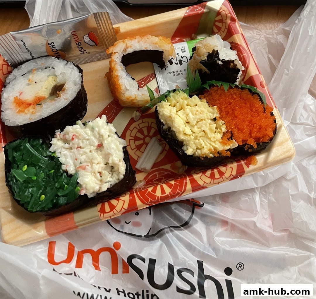A tray of assorted sushi rolls and gunkan maki with a packet of soy sauce.