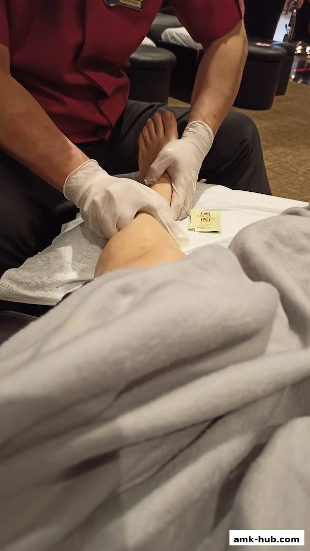 A therapist in gloves massages a customer's foot with oil.