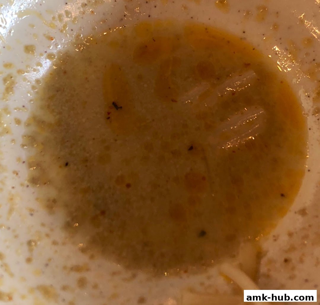 A close-up shot of a bowl of laksa soup with noodles and a rich broth.