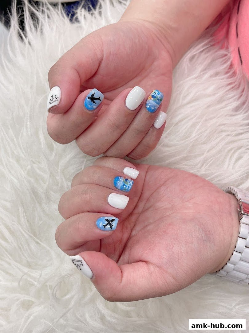 Close-up of hands with white nails featuring airplane and crown nail art.