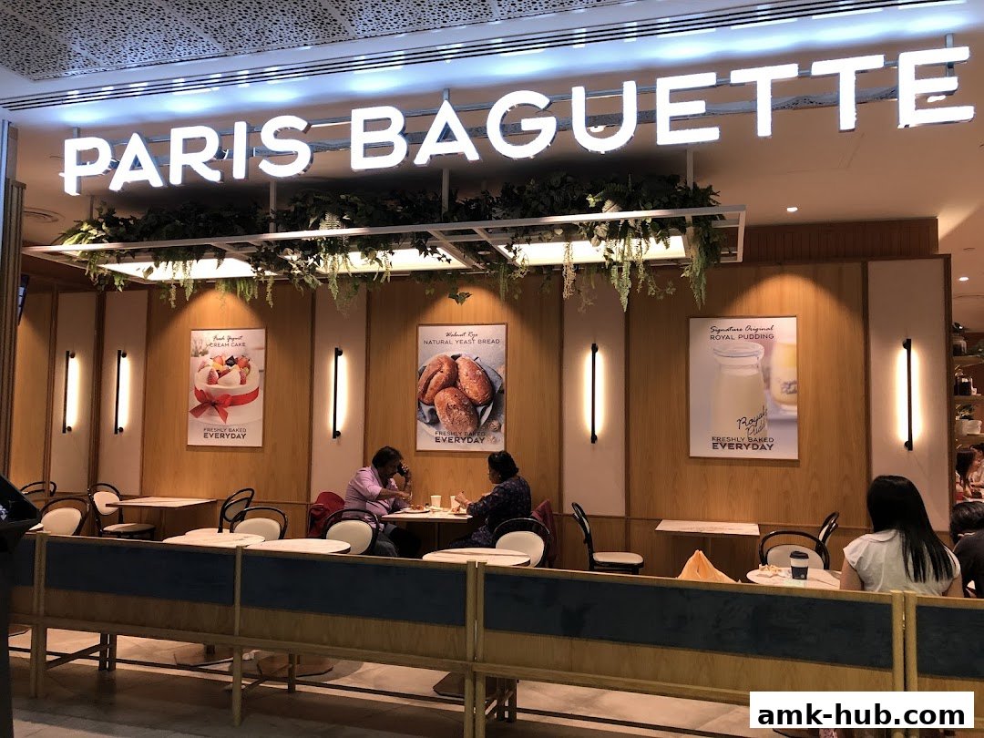 Paris Baguette shop interior with seating and promotional posters for cakes and bread.