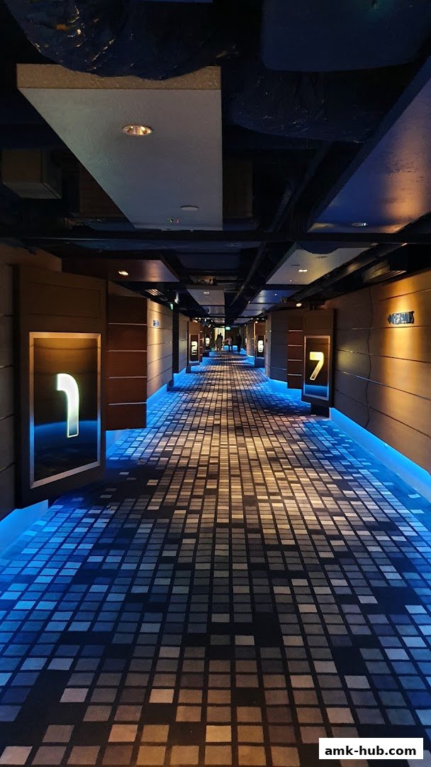 A long, dimly lit corridor with illuminated room numbers and a patterned carpet.