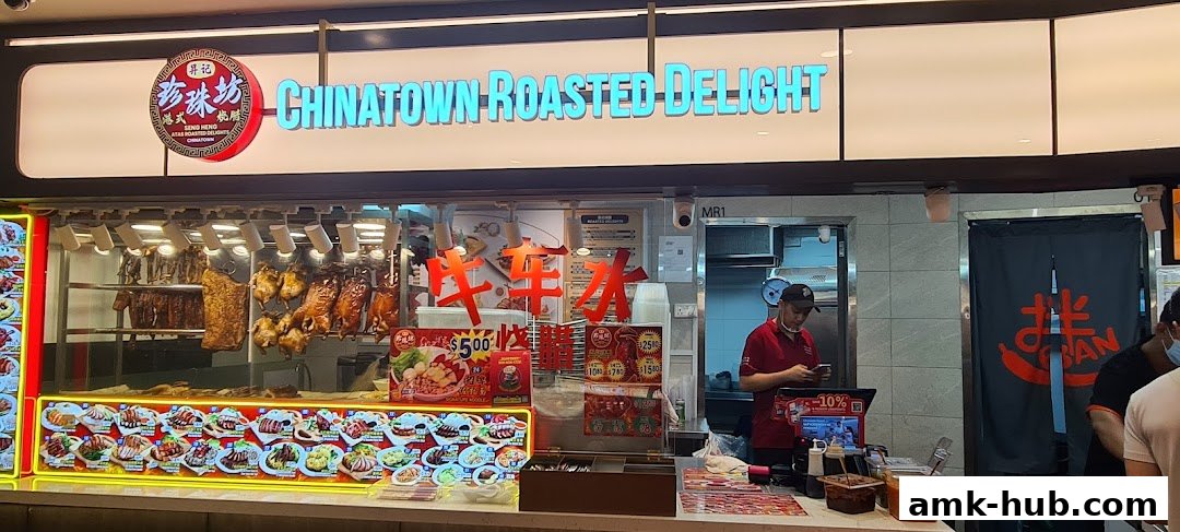 A food stall displaying various roasted meats and dishes with a prominent sign.