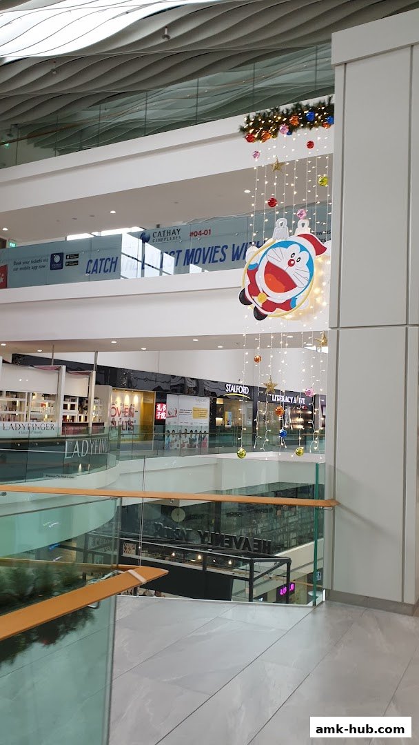 A shopping mall interior with various shops and festive decorations, including a Doraemon cutout.