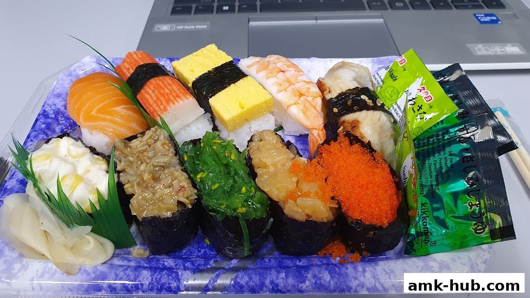 A platter of assorted sushi with various toppings and condiments, placed on a laptop.