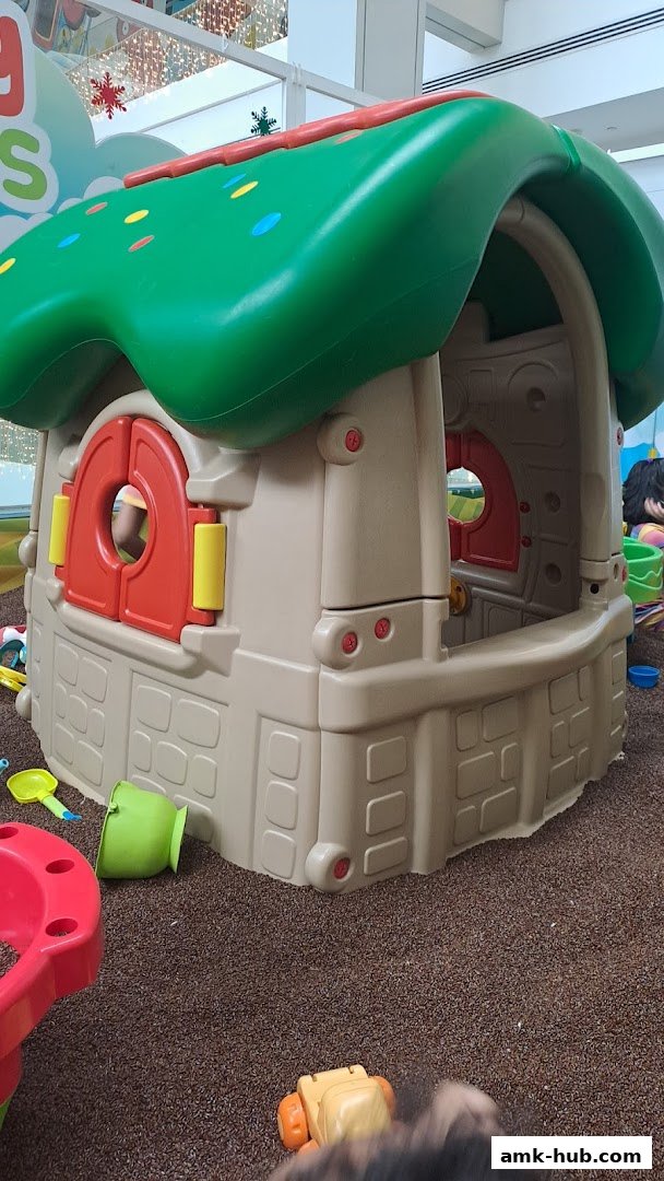 A colorful playhouse structure with sand and toys, designed for children's entertainment.