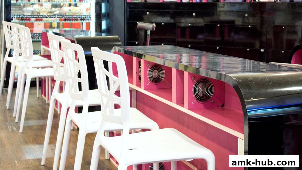 Interior shot of Nail Palace with white chairs lined up at a pink and chrome nail desk.
