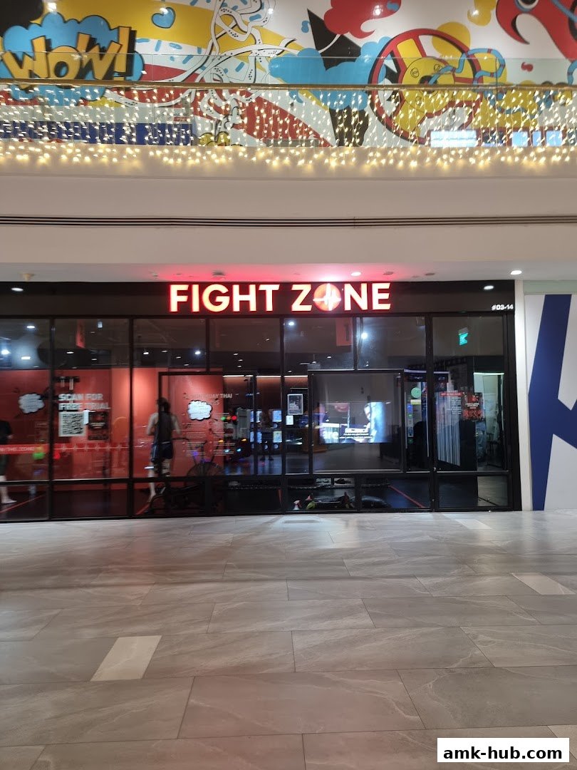 The exterior of Fight Zone, a fitness studio, with a bright neon sign and large glass windows.