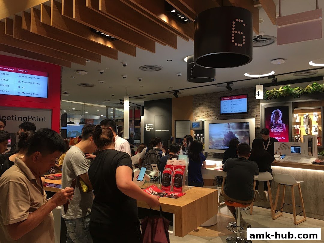 Customers queue inside a busy Singtel shop with digital displays and product showcases.