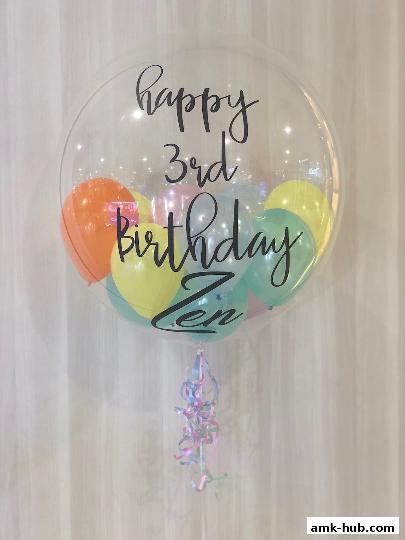 A clear bubble balloon filled with colorful balloons, wishing 'happy 3rd birthday Zen'.