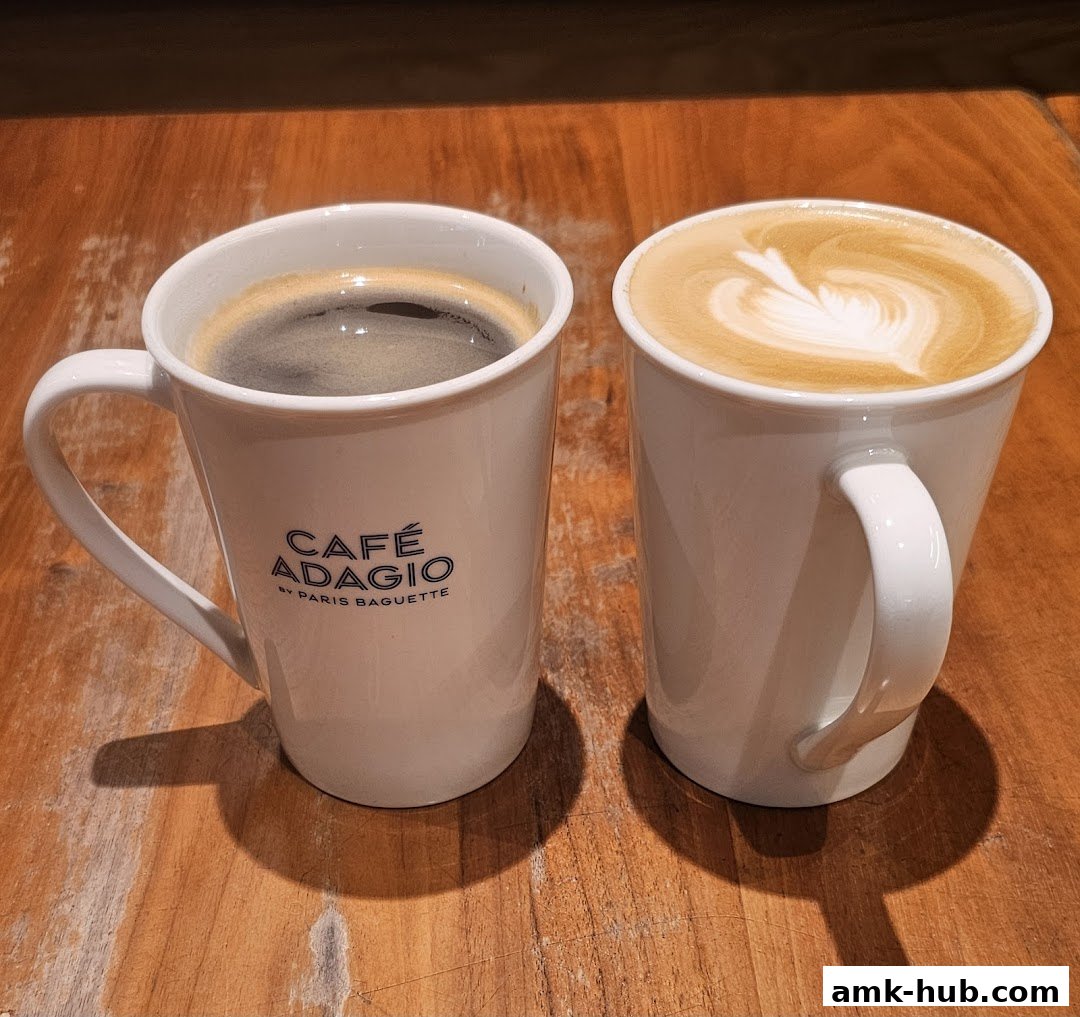 Two white mugs of coffee, one black and one with latte art, on a wooden table.