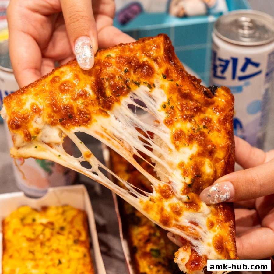A slice of cheesy pizza with a long cheese pull, held by two hands.