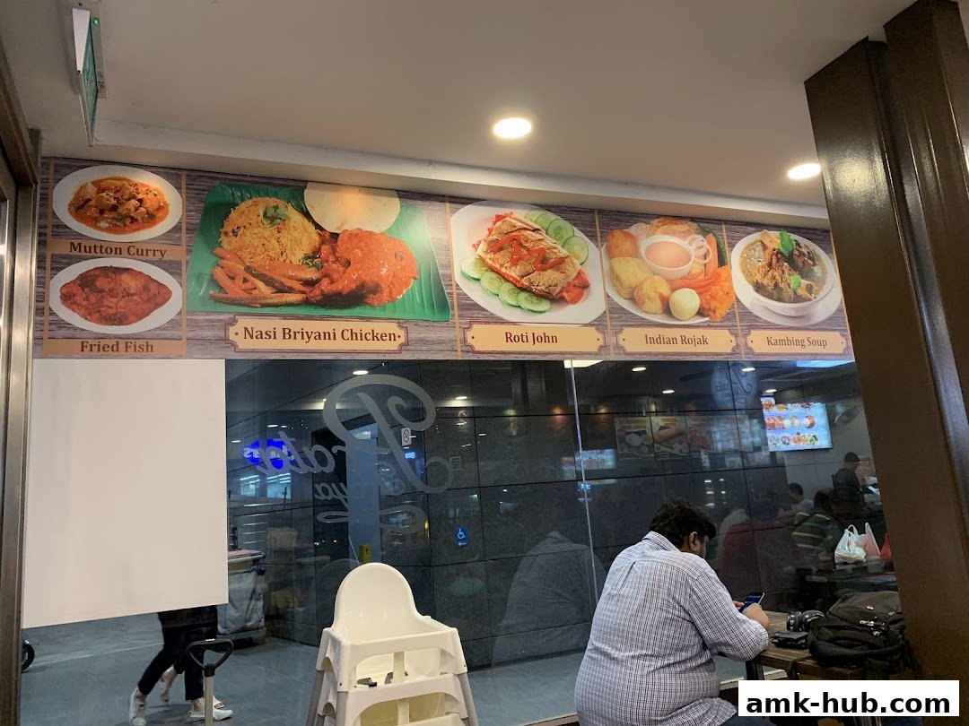 A wall display of food items at Prata Raya restaurant with customers seated inside.