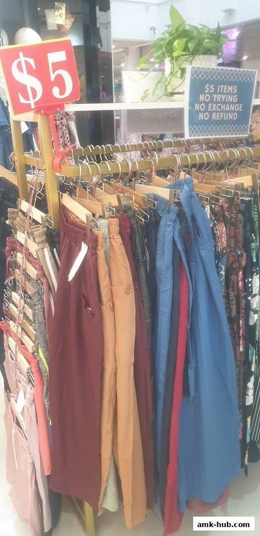 A display of colorful pants and clothing items on hangers with a $5 price tag.