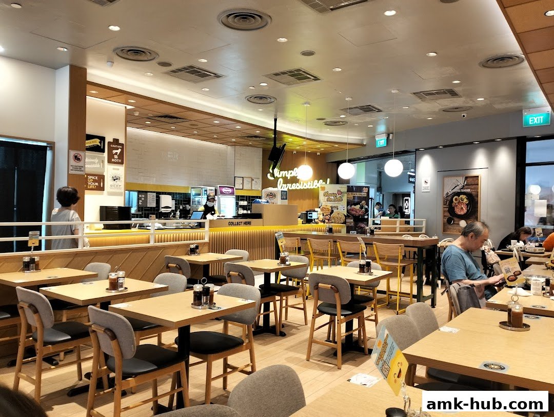 Interior view of a Pepper Lunch restaurant with tables, chairs, and a counter.