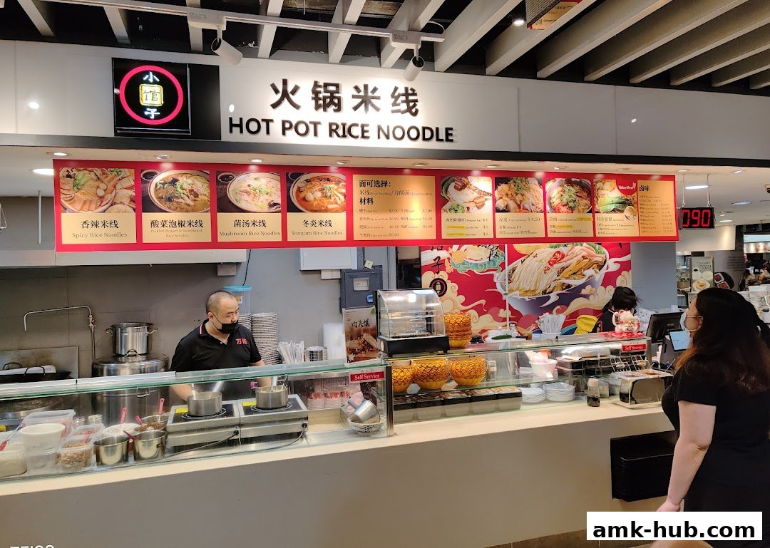 A food stall with a menu displaying various hot pot rice noodle dishes and ingredients.
