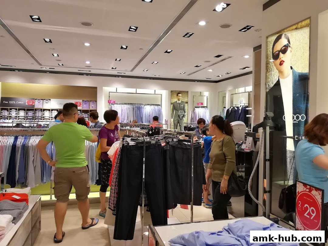 Shoppers browse clothing racks inside a well-lit G2000 store, featuring formal wear and casual attire.