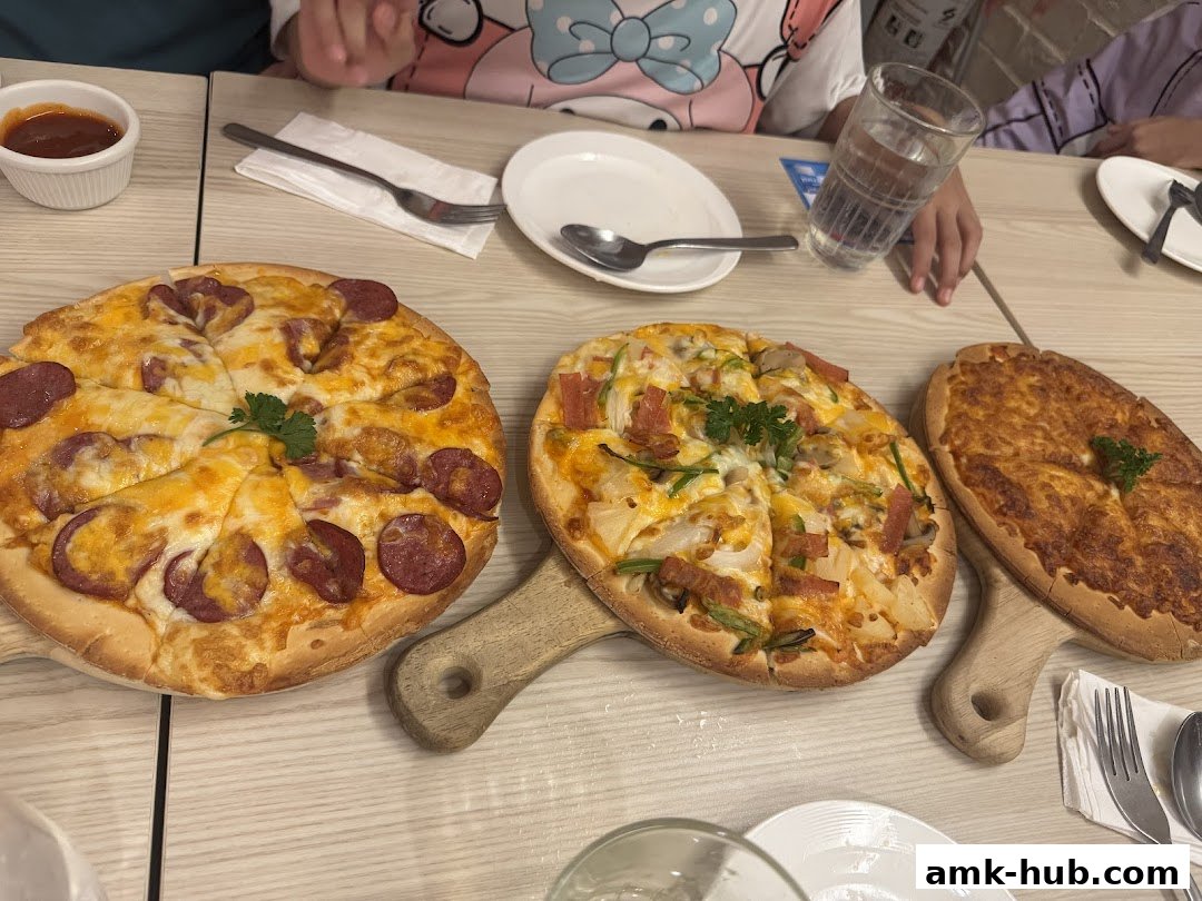 Three pizzas are served on wooden boards with a side of dipping sauce and drinks.