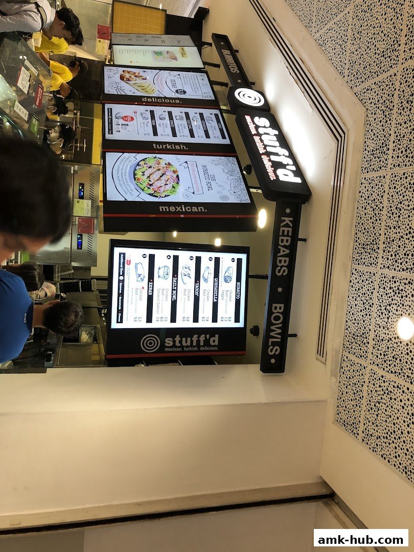 A food stall with digital menus displaying Mexican, Turkish, and delicious food options.