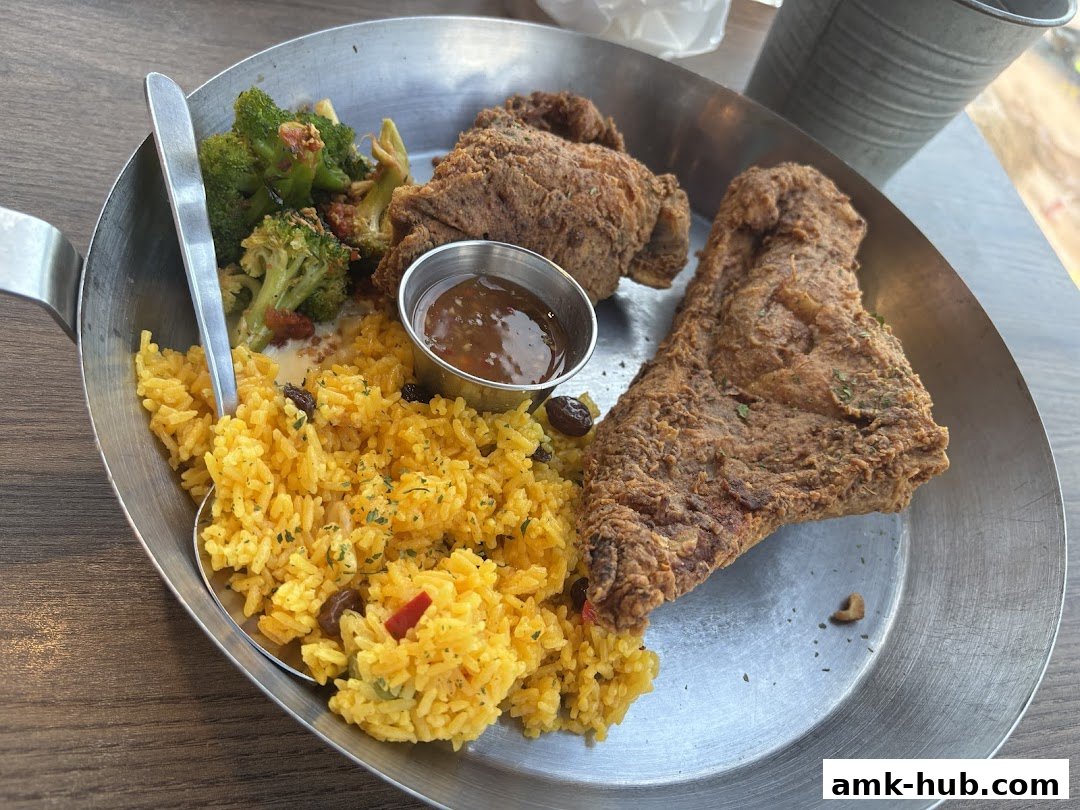 A plate of fried chicken with rice and broccoli served in a metal pan.
