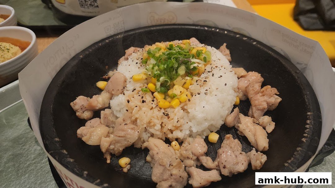 A sizzling hot plate of rice with chicken, corn, and green onions, served at Pepper Lunch.