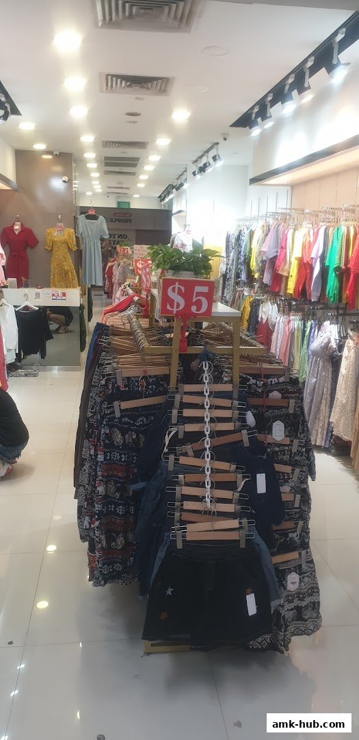 Interior view of a clothing store with racks of colorful apparel and a prominent '$5' sale sign.