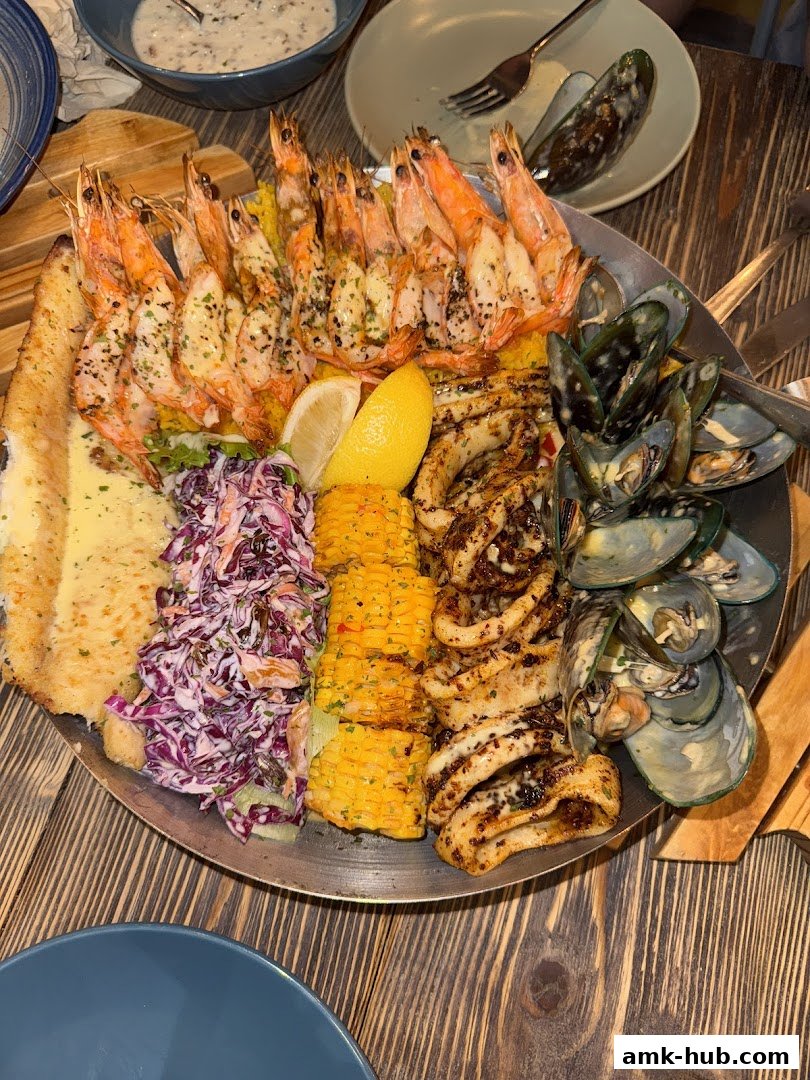 A large platter of grilled seafood including shrimp, calamari, mussels, and fish with corn and coleslaw.