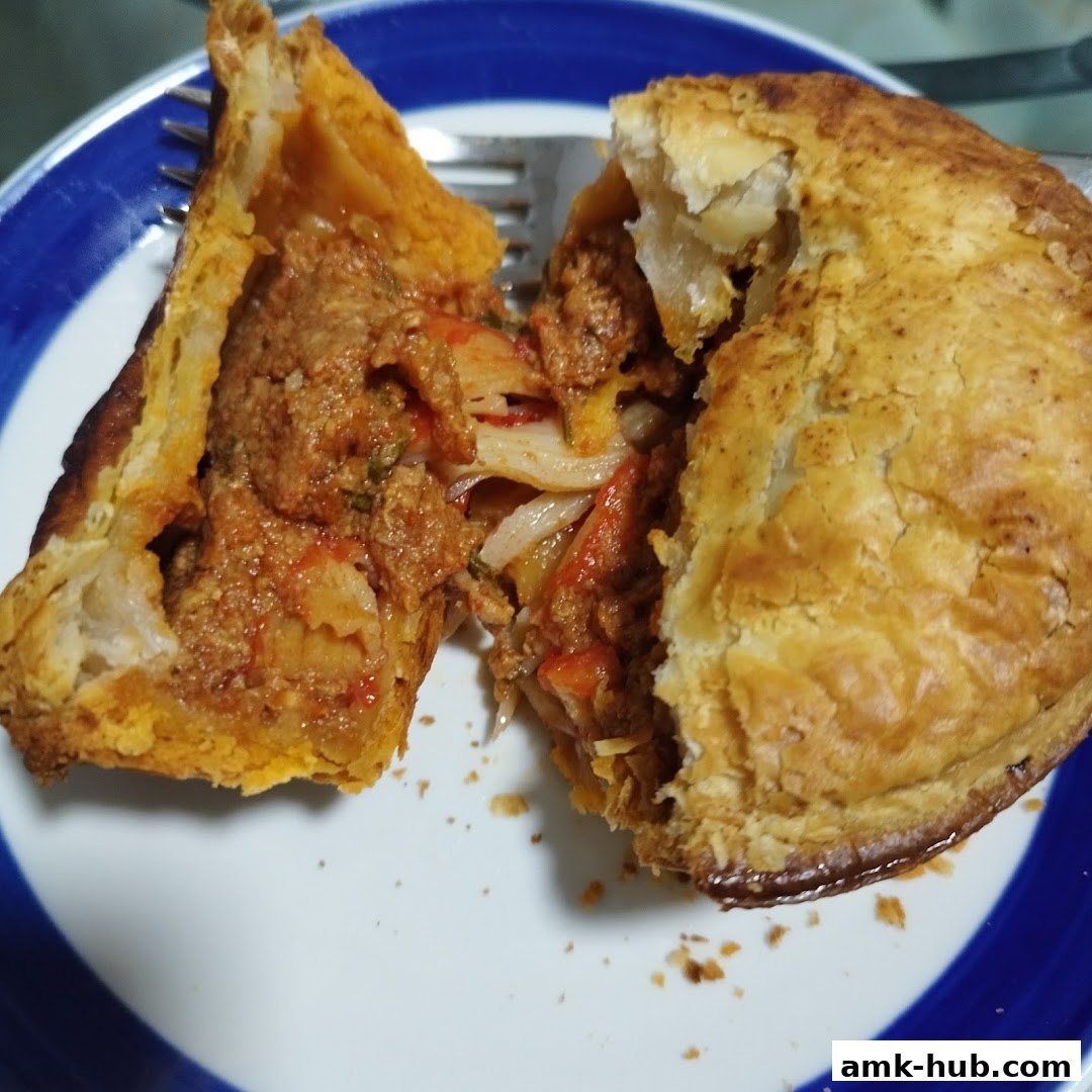 A close-up of a savory pie, cut in half, revealing a hearty filling.