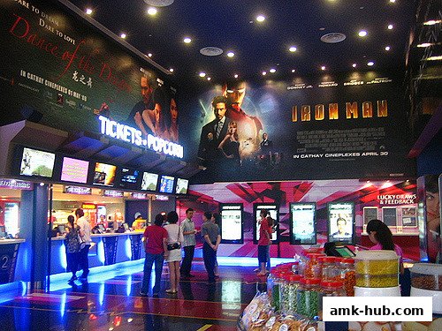 Interior of a cinema lobby with movie posters, ticket counters, and snack displays.