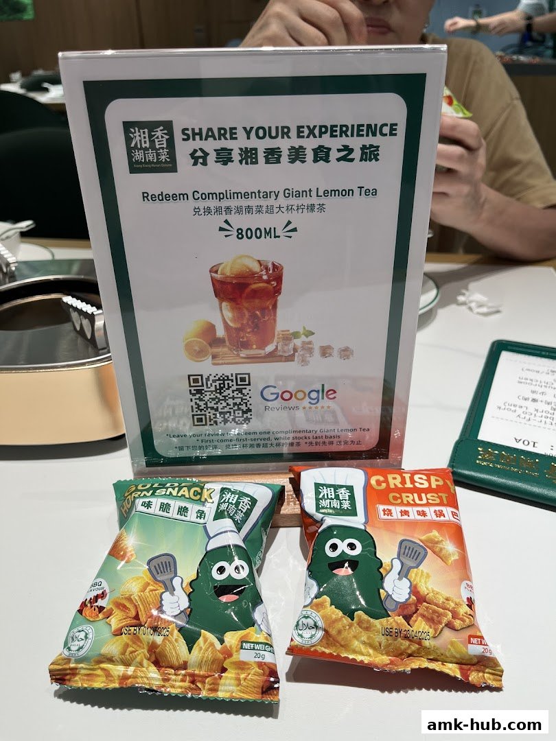 A sign offering a complimentary lemon tea for sharing an experience, with snacks in the foreground.