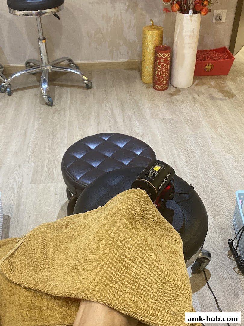 A person's foot is being treated with a nail lamp and covered with a towel.
