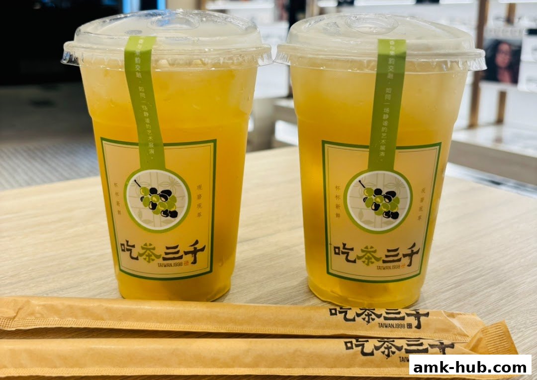 Two cups of yellow beverage with grape branding and two packaged straws.