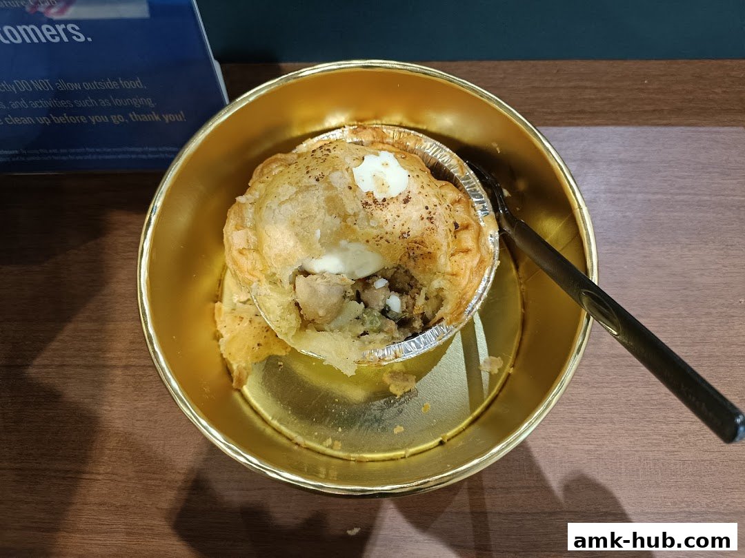 A golden bowl holds a savory chicken pie with a fork resting on the side.