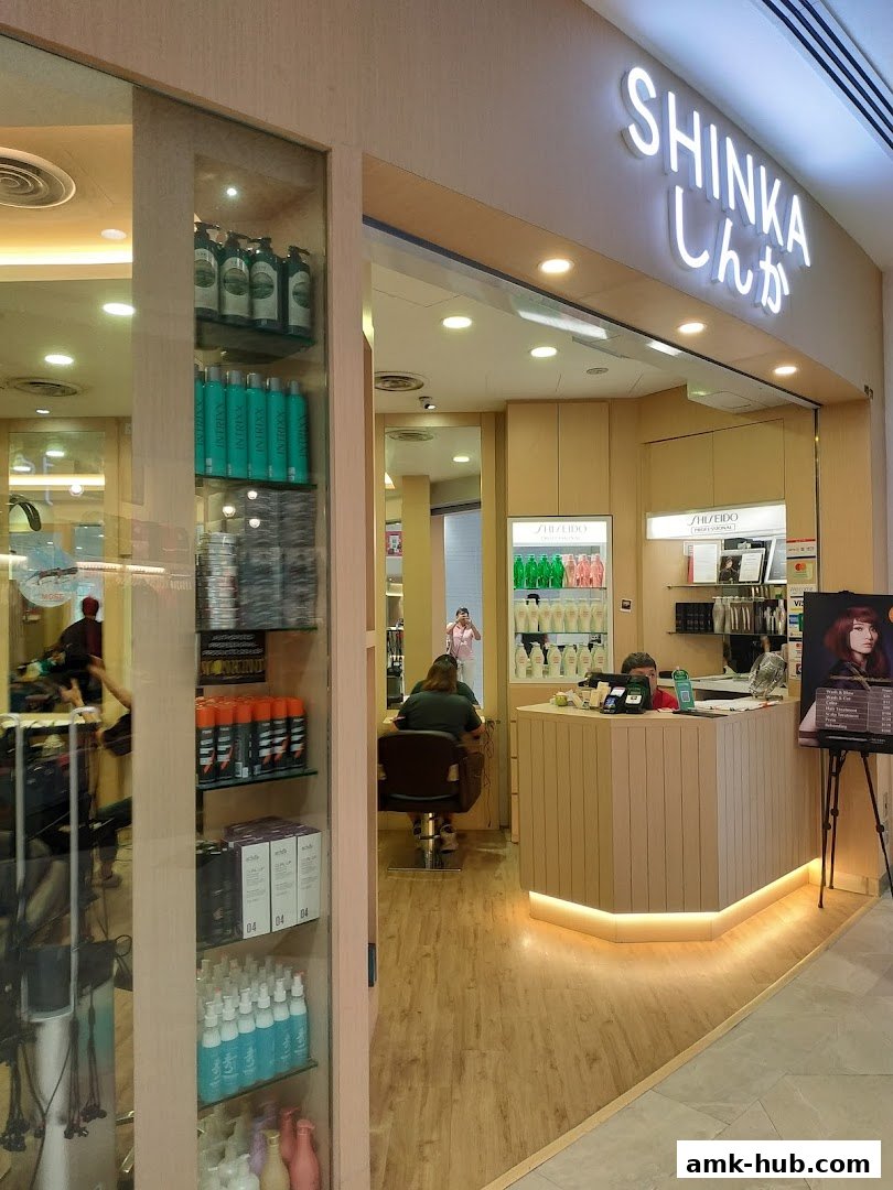 The entrance of a modern hair salon named Shinka, with products displayed and a reception desk.