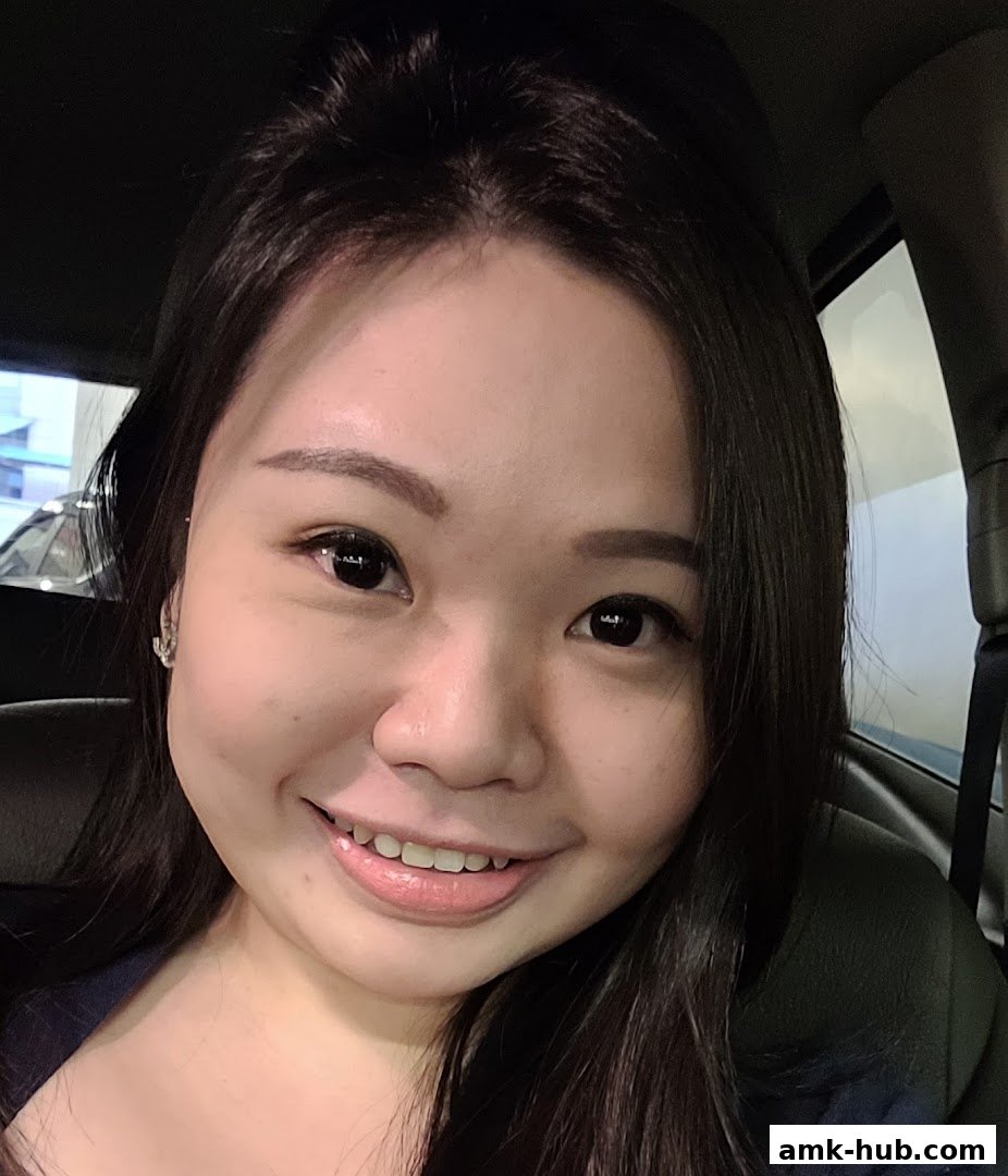 A close-up selfie of a smiling young woman with dark hair and makeup.