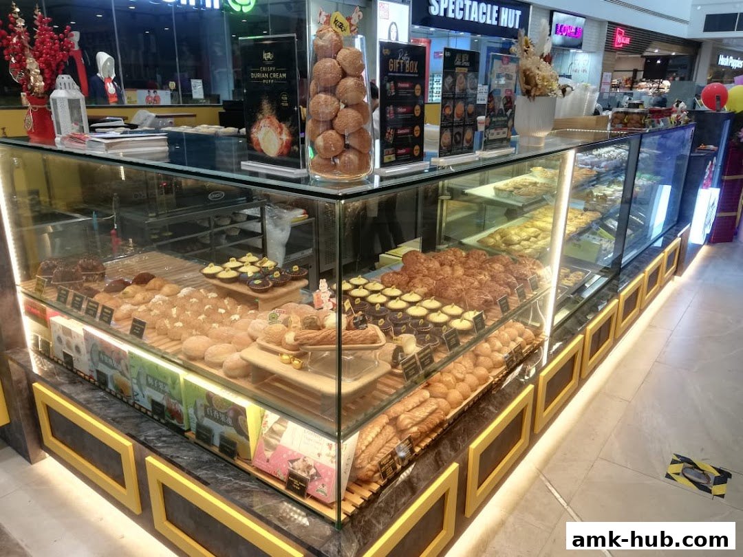 A display case filled with various pastries, buns, and tarts at a bakery shop.