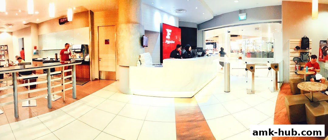 Interior view of Fitness First gym with reception, seating area, and gym equipment visible.