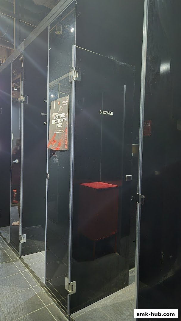 Modern shower cubicles with black glass doors and a promotional poster inside one.