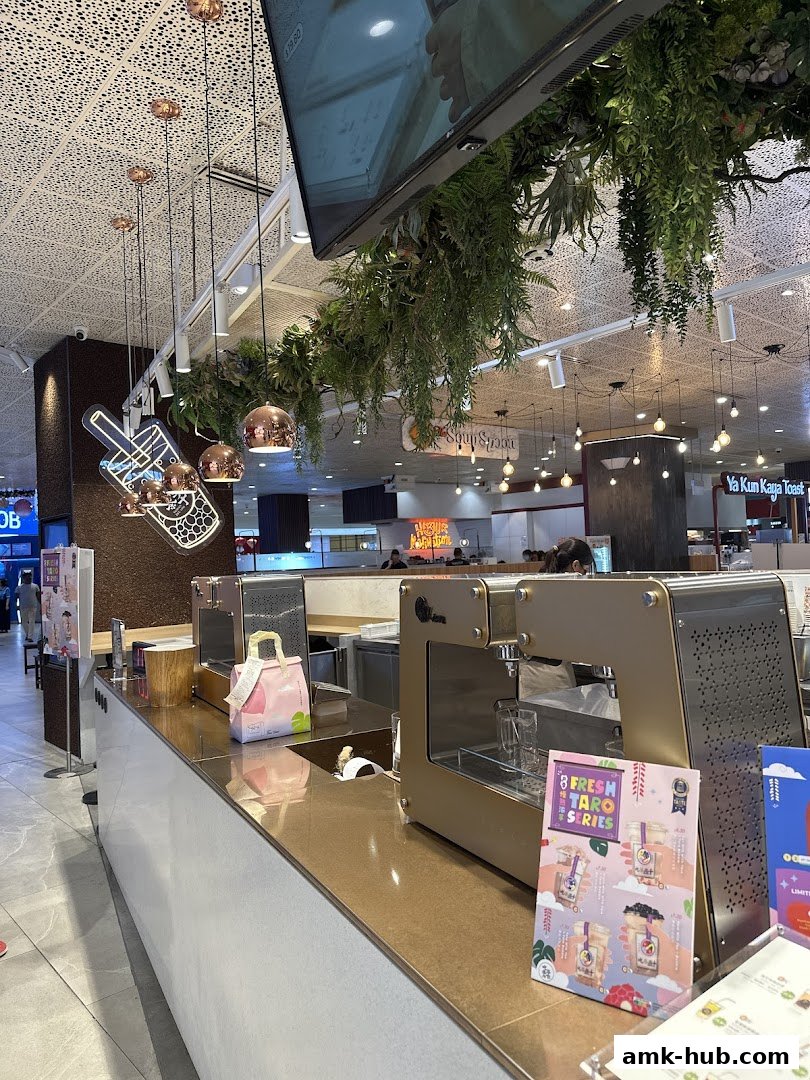 Interior shot of a modern bubble tea shop counter with decorative plants and lighting.