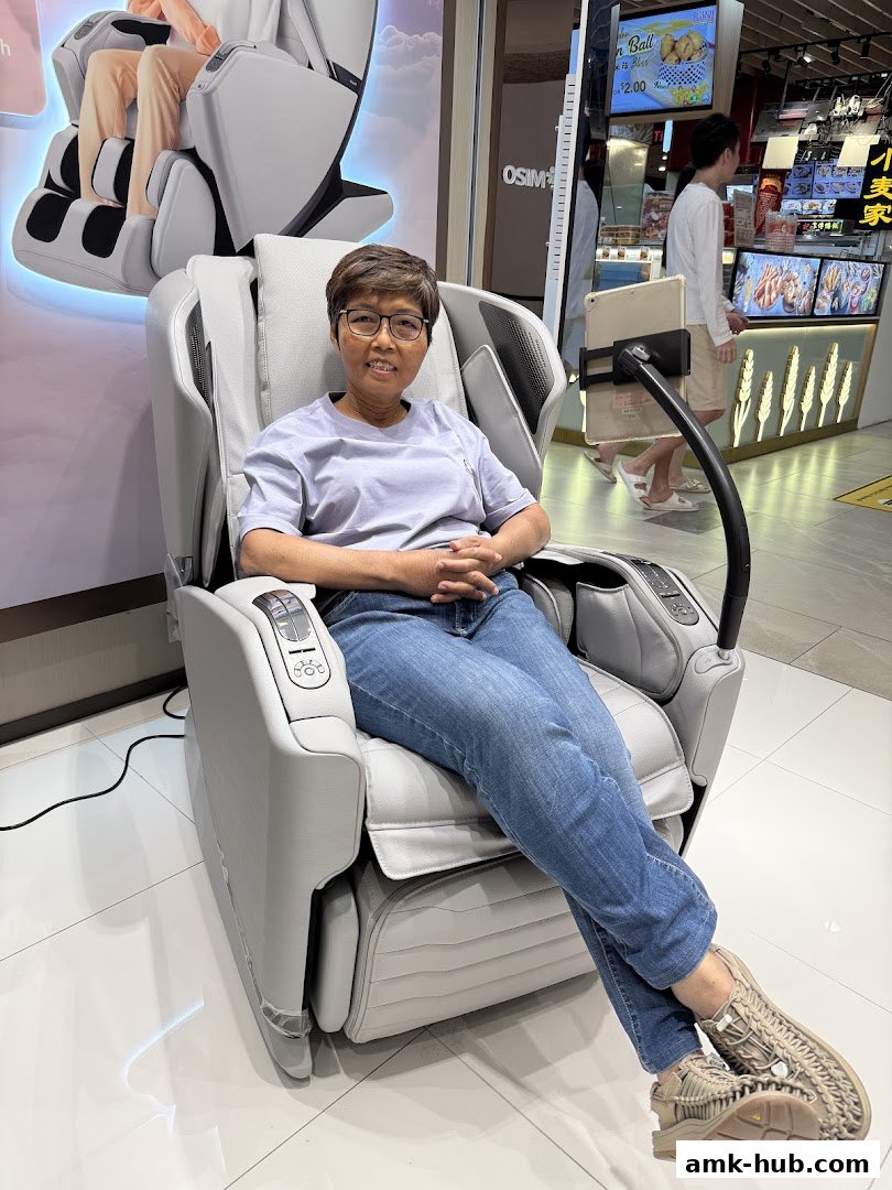 A woman sits in a modern massage chair in a brightly lit retail store.