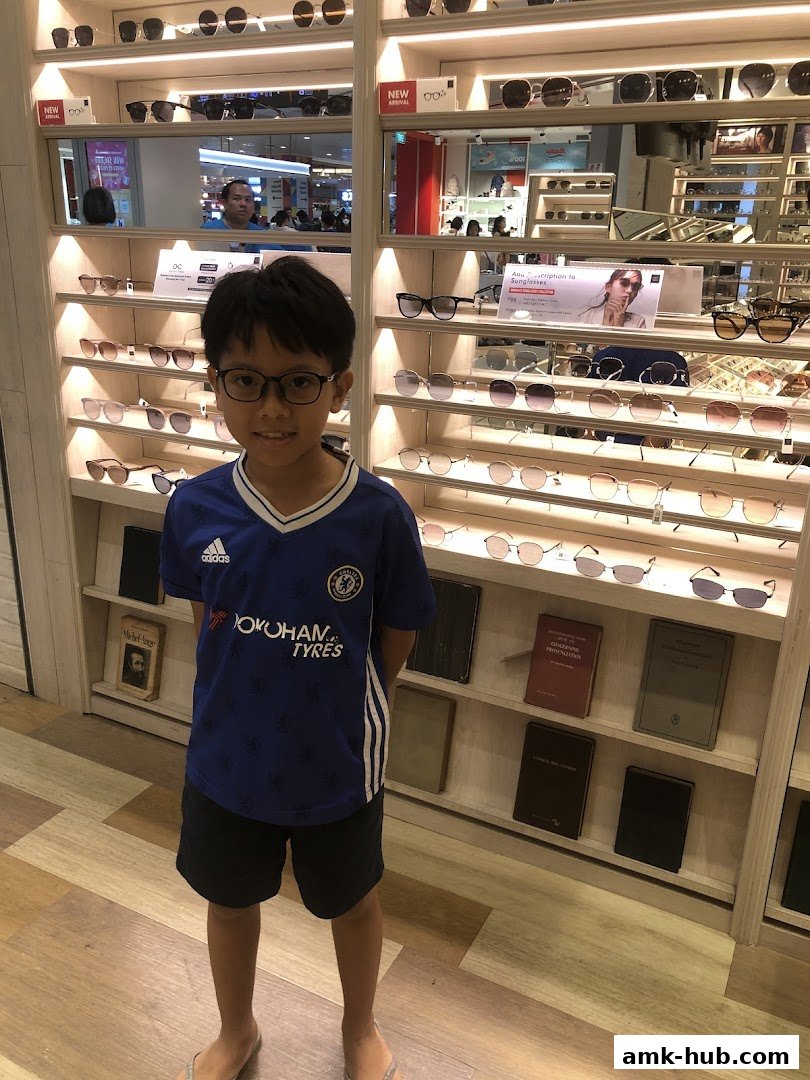 A young boy stands in front of a display of eyeglasses at OWNDAYS AMK Hub.