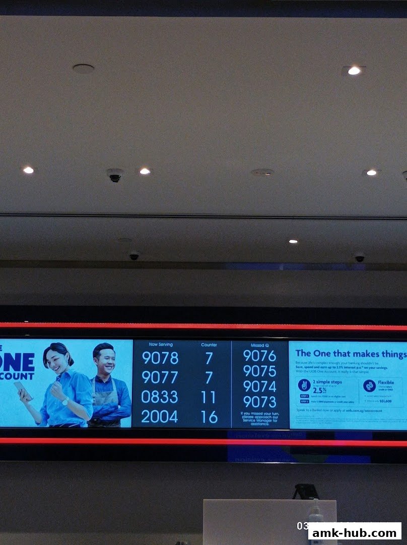 A digital display shows queue numbers and banking information at a UOB branch.