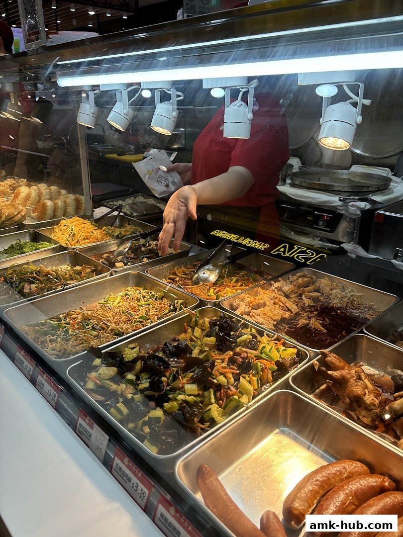 A food display with various dishes and a staff member preparing food.