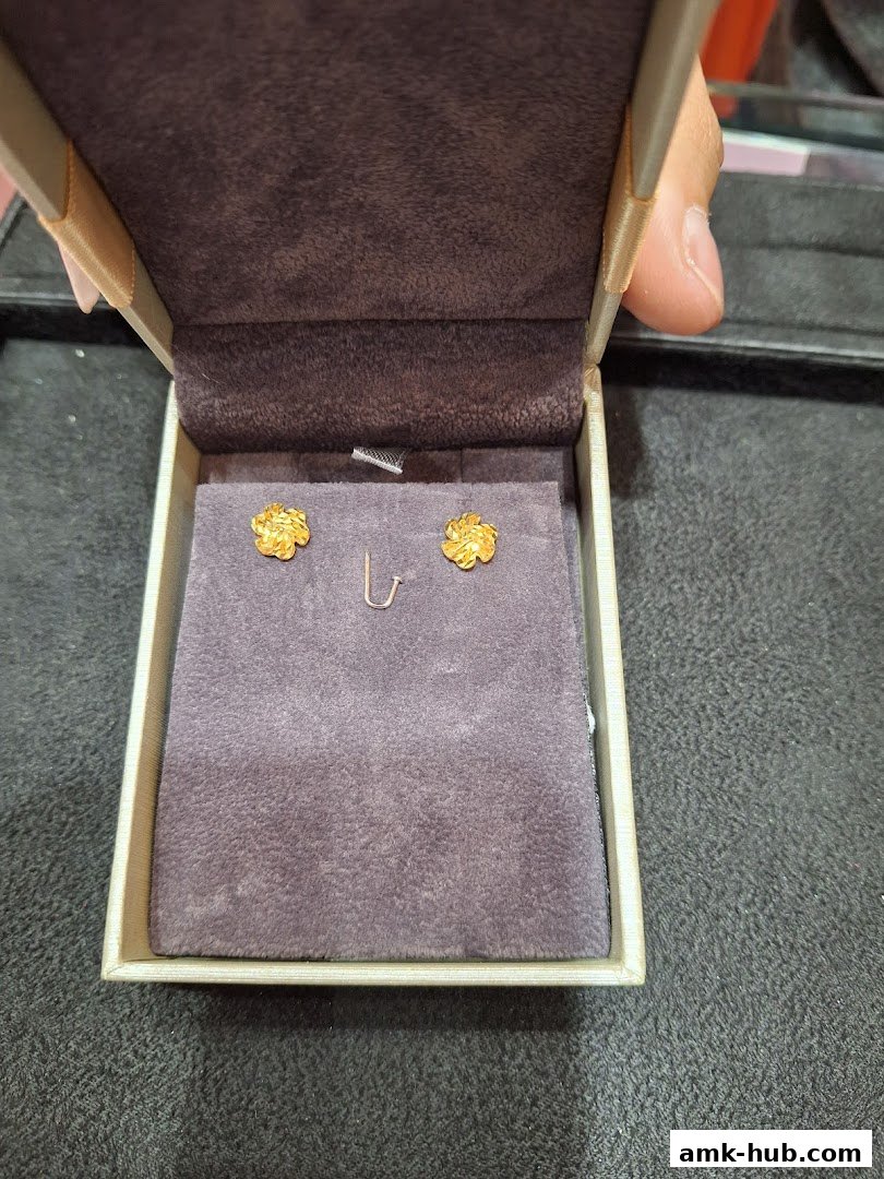 A pair of gold floral stud earrings displayed in an open jewelry box.