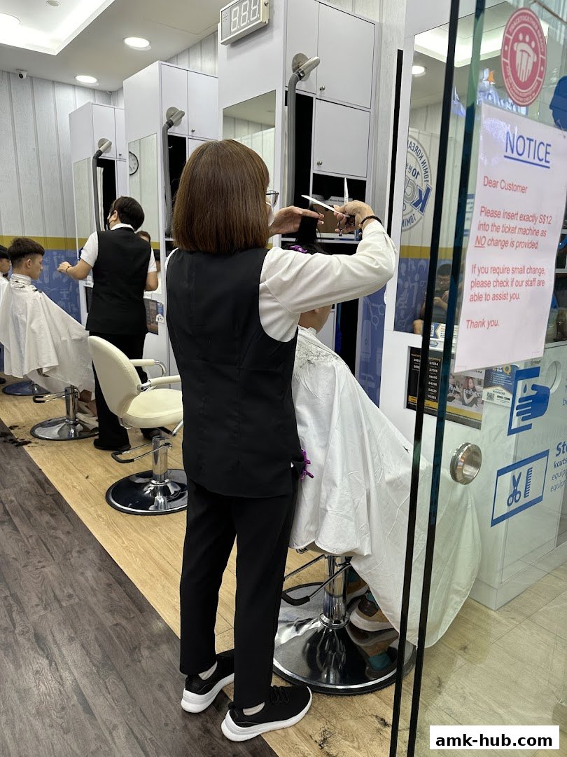 A hairdresser is cutting a customer's hair in a modern salon with multiple workstations.