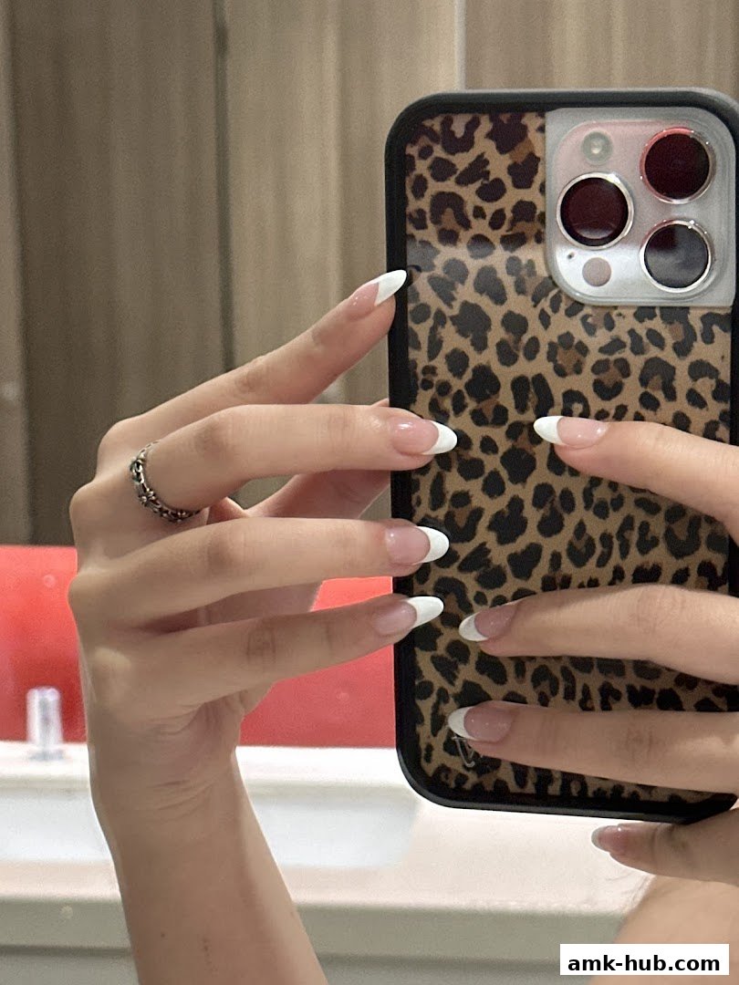 A person's hands with French manicured nails holding a leopard-print phone case.