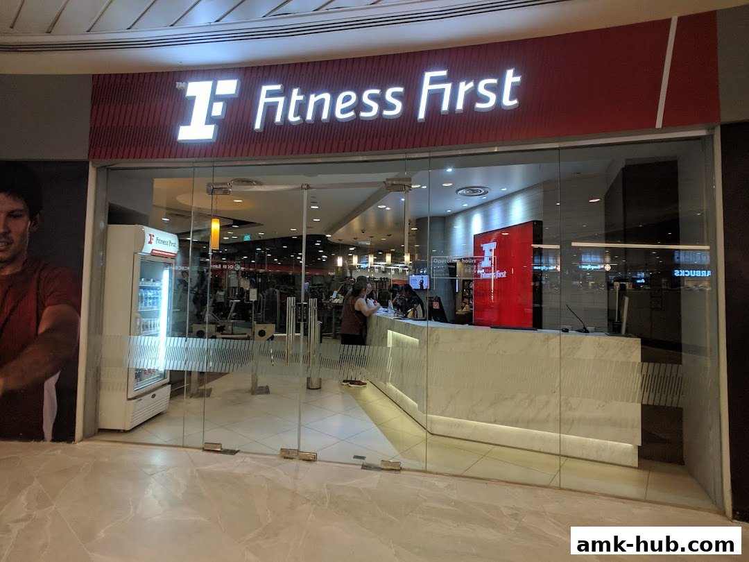 The entrance to Fitness First gym with a reception desk and exercise equipment visible inside.