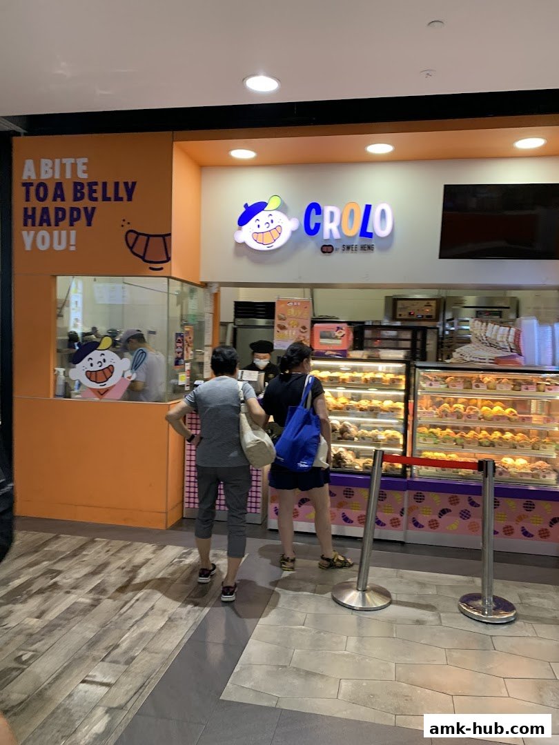Customers queue at CROLO by Swee Heng bakery, showcasing a variety of pastries in display cases.