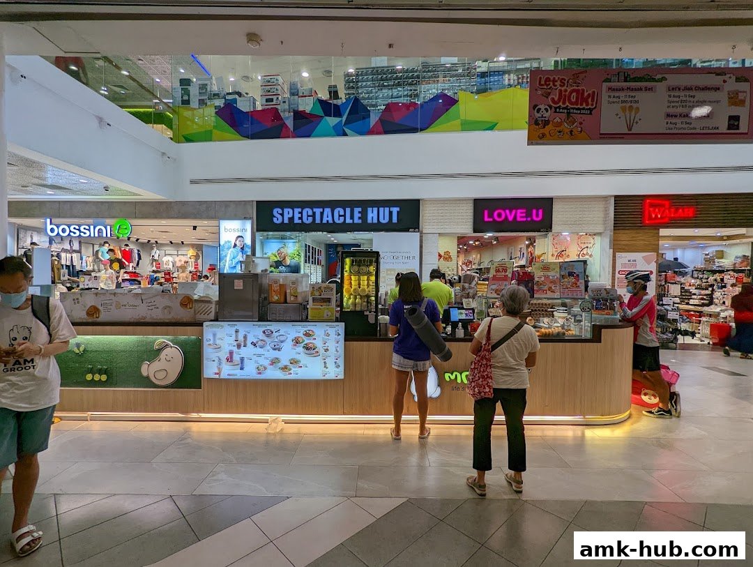 A food stall in a shopping mall with customers ordering and browsing the menu.